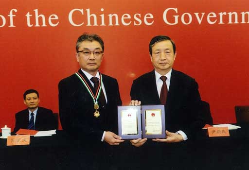 馬凱・国務院副総理(右)から楯とメダルを授与される齋藤昌義(JIRCAS職員)